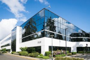 Immeuble de bureaux contemporain à Redmond avec verre réfléchissant et verdure luxuriante, capturé lors d'une journée ensoleillée.