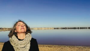 A woman standing on a beach looking up at the sky
