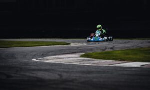 Photo dynamique d'un pilote de karting filant à toute vitesse dans une courbe de piste, mettant en valeur le frisson du sport automobile.