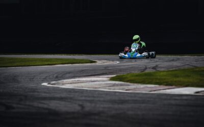 Photo dynamique d'un pilote de karting filant à toute vitesse dans une courbe de piste, mettant en valeur le frisson du sport automobile.