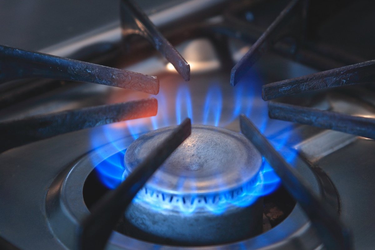 Flamme bleue sur un fourneau à gaz, grille métallique au-dessus