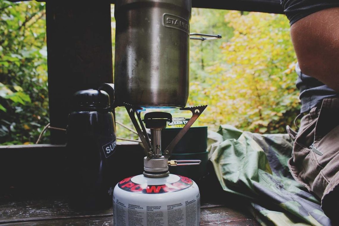 Cuisinière de camping avec casserole et bouteille d'eau sur table en forêt